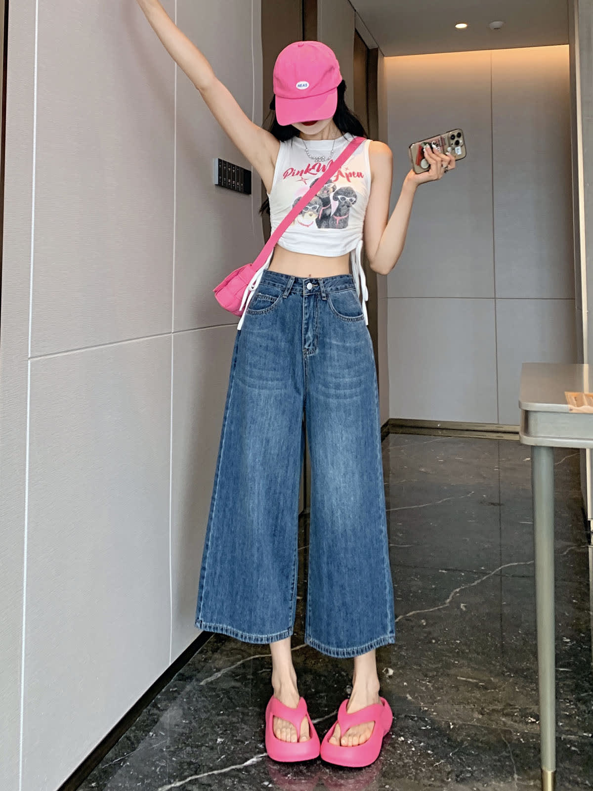 YEEYEEWang Wide-Leg Jeans in Vintage Blue, Asian-fit cut, full-body front standing pose holding phone, pink cap, white graphic tank and pink crossbody bag.