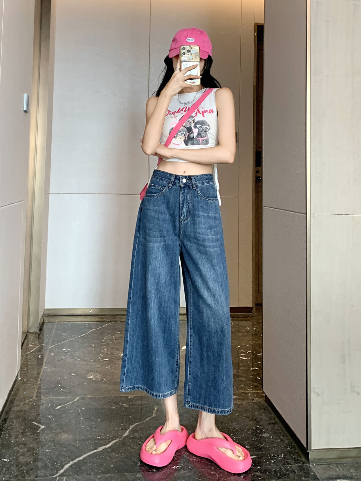 YEEYEEWang Wide-Leg Jeans in Vintage Blue, Asian-fit cut, full-body front pose holding phone at face, pink cap and white graphic tank top.