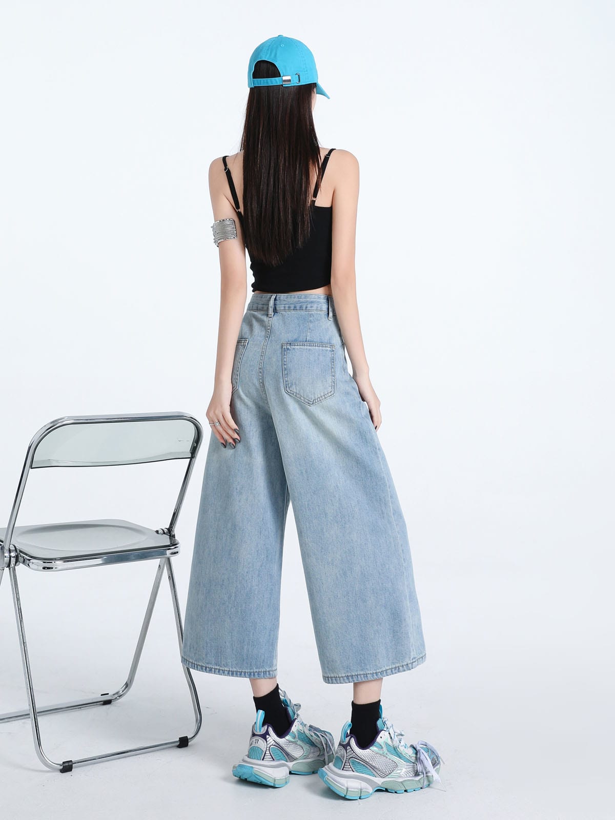 YEEYEEWang Wide-Leg Jeans in Light Blue, Asian-fit cut, full-body back standing pose beside a clear folding chair, back patch pockets visible, blue cap.