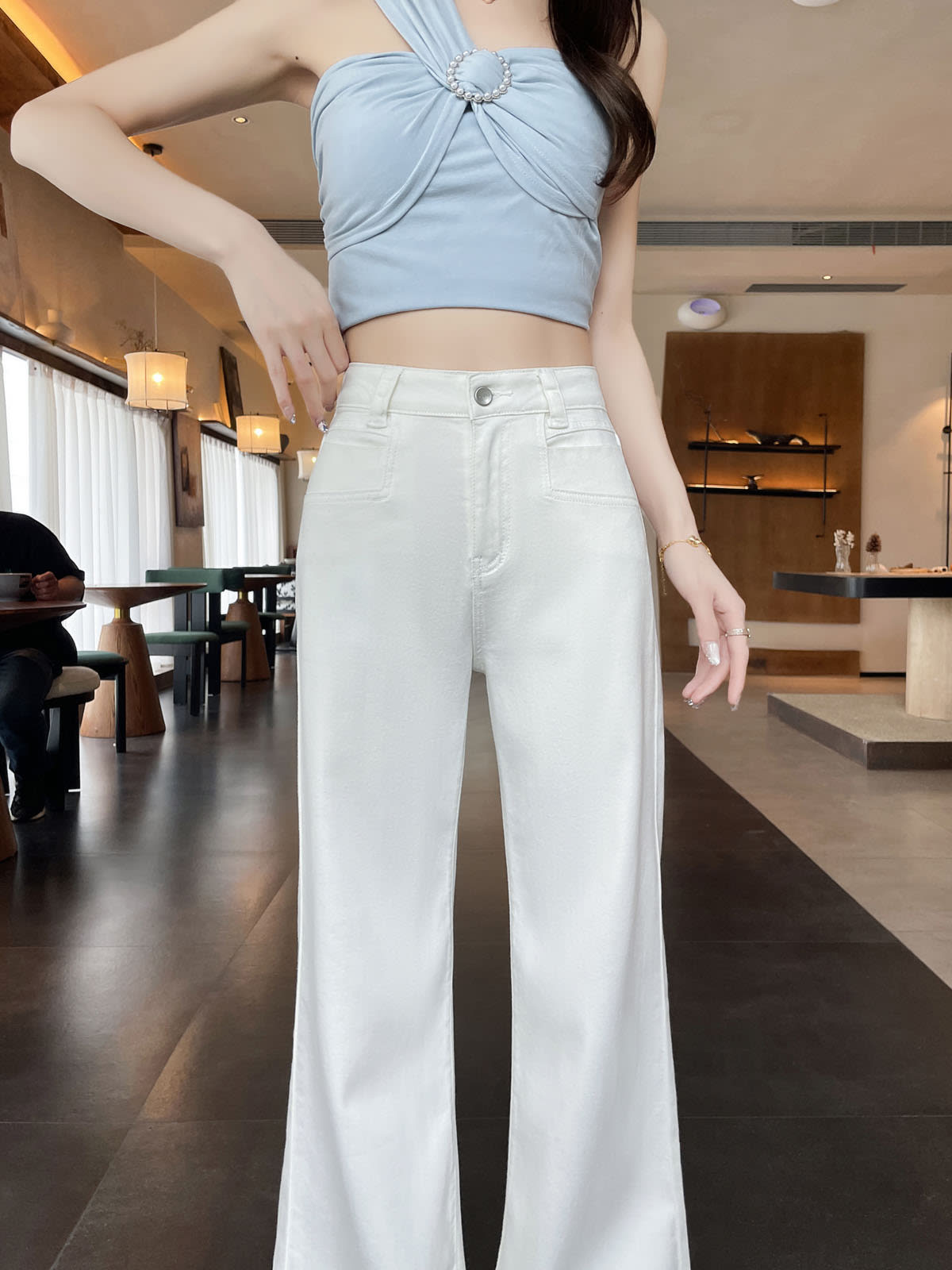 YEEYEEWang Flare Jeans in White, Asian-fit cut, waist-down front view of high waistband and front patch pockets, hand near waistband.