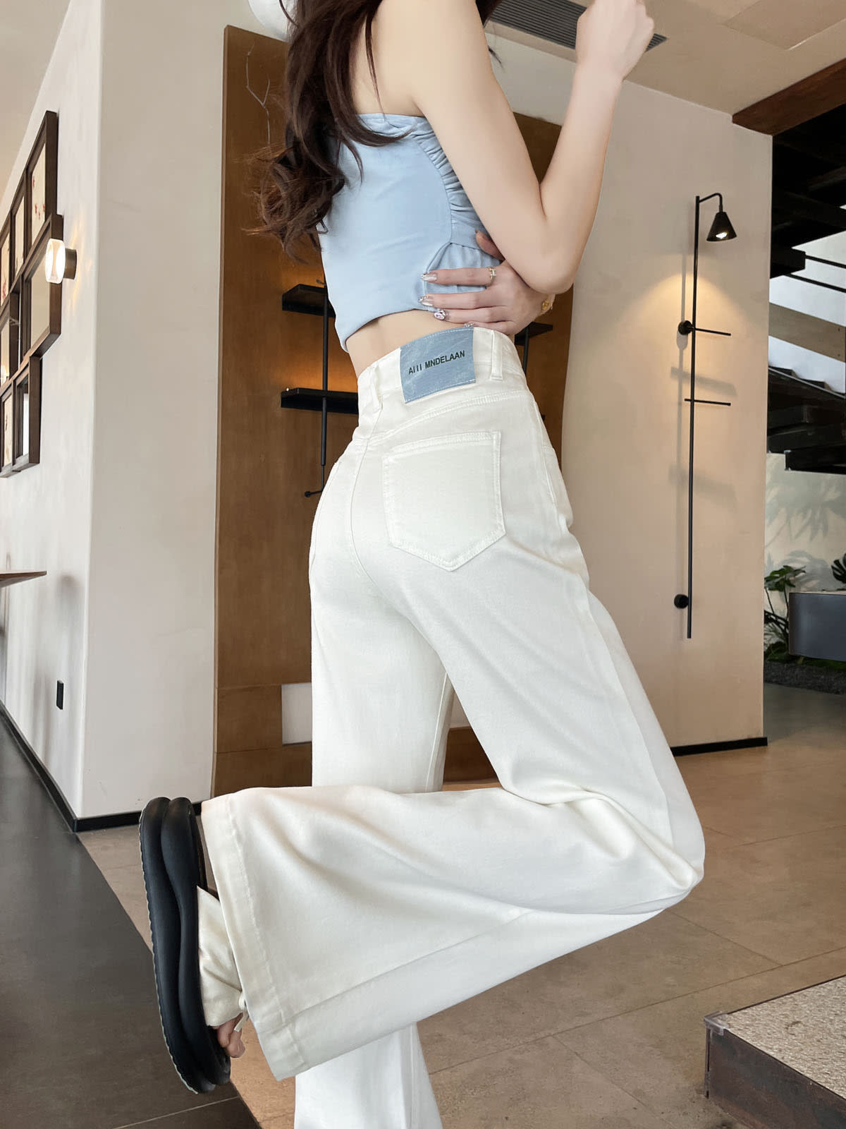 YEEYEEWang Flare Jeans in White, Asian-fit cut, waist-down back view in leg-kick pose showing back patch pocket.