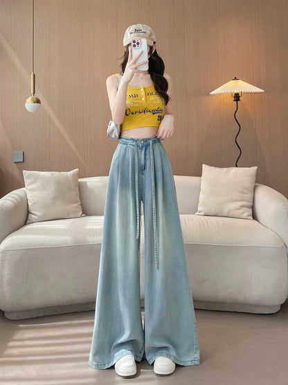YEEYEEWang Wide-Leg Jeans in Light Blue, Asian-fit cut, full-body front standing pose holding phone at face, yellow tank and beige cap with silver shoulder bag.