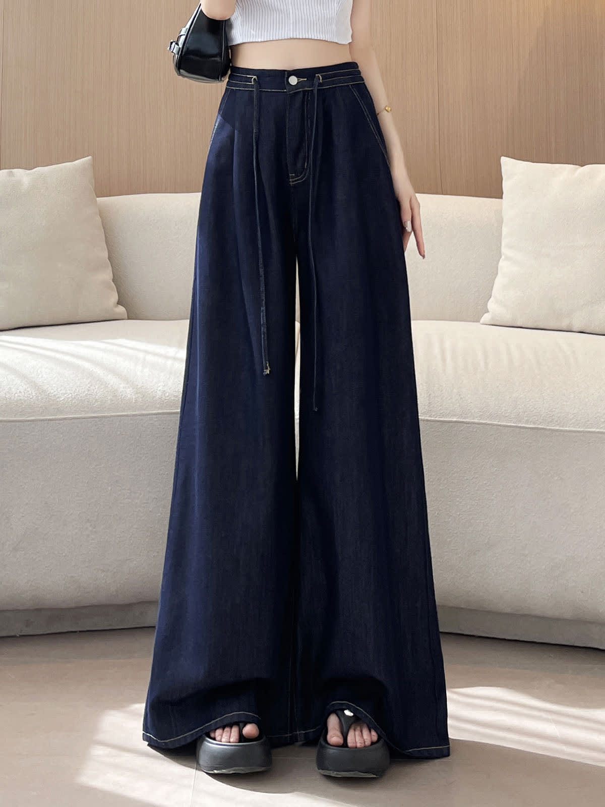 YEEYEEWang wide-leg jeans in Denim Blue, Asian-fit cut, waist-down front view of flowing wide legs with drawstring waist and black shoulder bag, variant thumbnail.
