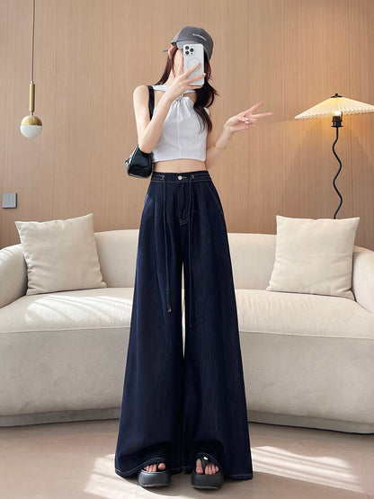 YEEYEEWang wide-leg jeans in Denim Blue, Asian-fit cut, full-body front pose holding phone at face, cap and striped halter top, black bag on shoulder.