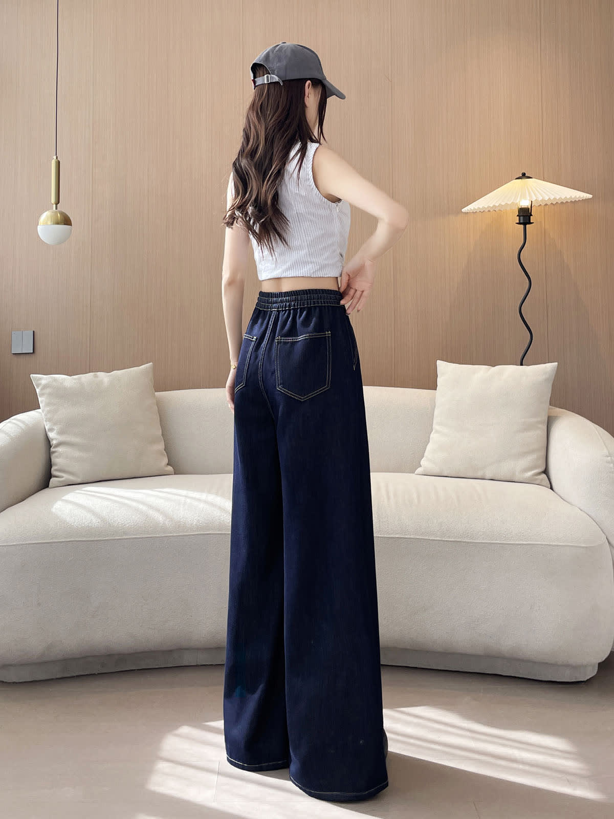 YEEYEEWang wide-leg jeans in Denim Blue, Asian-fit cut, full-body back view with elastic back waistband, back patch pockets and long wavy hair, standing indoors.