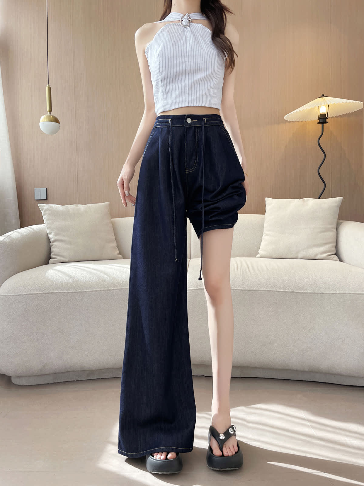 YEEYEEWang wide-leg jeans in Denim Blue, Asian-fit cut, full-body front view with one pant leg pulled up to the thigh showing the extra-wide leg opening, striped halter top.