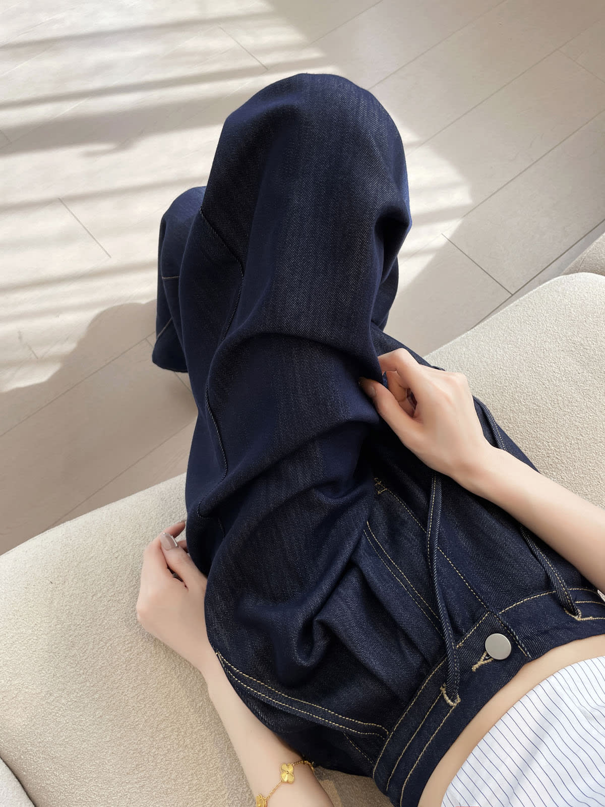 YEEYEEWang wide-leg jeans in Denim Blue, Asian-fit cut, close-up of hands lifting the wide leg fabric to show soft drape, contrast stitching and button detail visible.