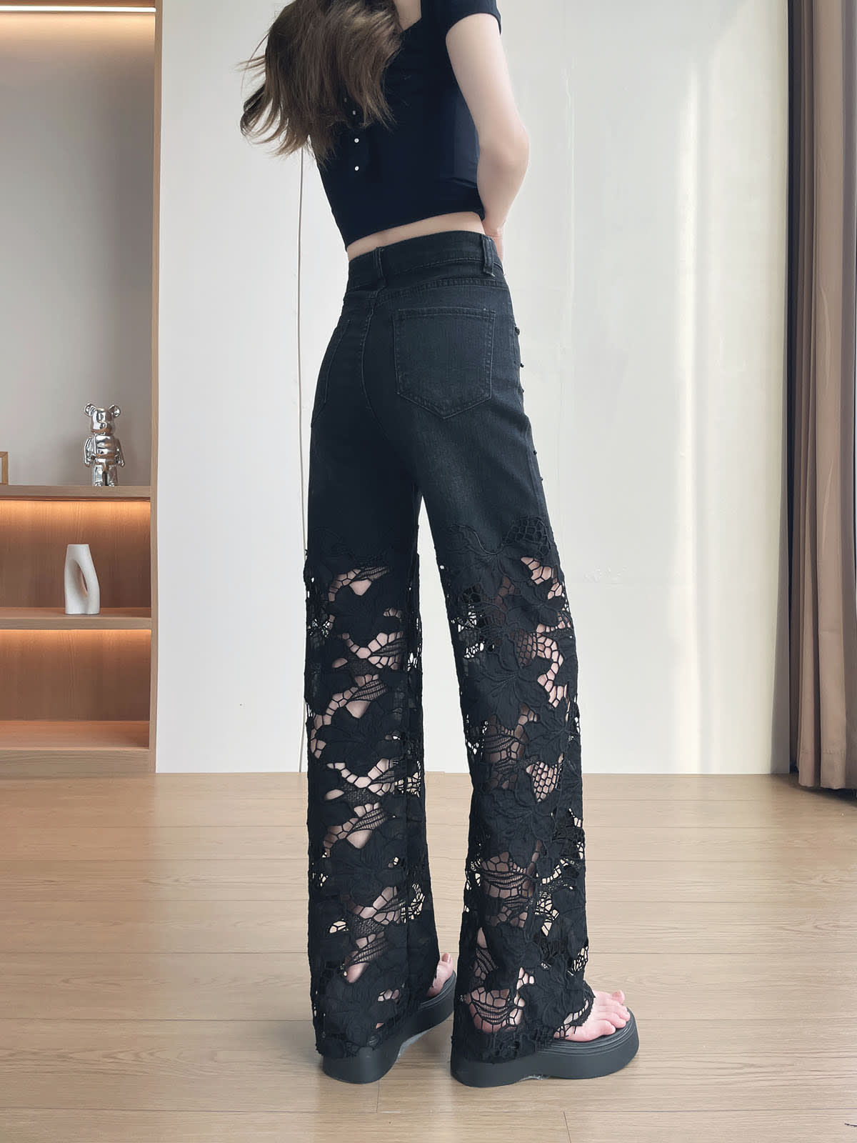 YEEYEEWang Wide-Leg Jeans in Solid Black, Asian-fit cut, full-body back view standing, plain back patch pockets and floral lace cutout wide legs with black platform sandals.