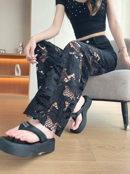 YEEYEEWang Wide-Leg Jeans in Solid Black, Asian-fit cut, waist-down view seated on sofa with legs crossed, floral lace cutout wide legs draped over platform sandals.