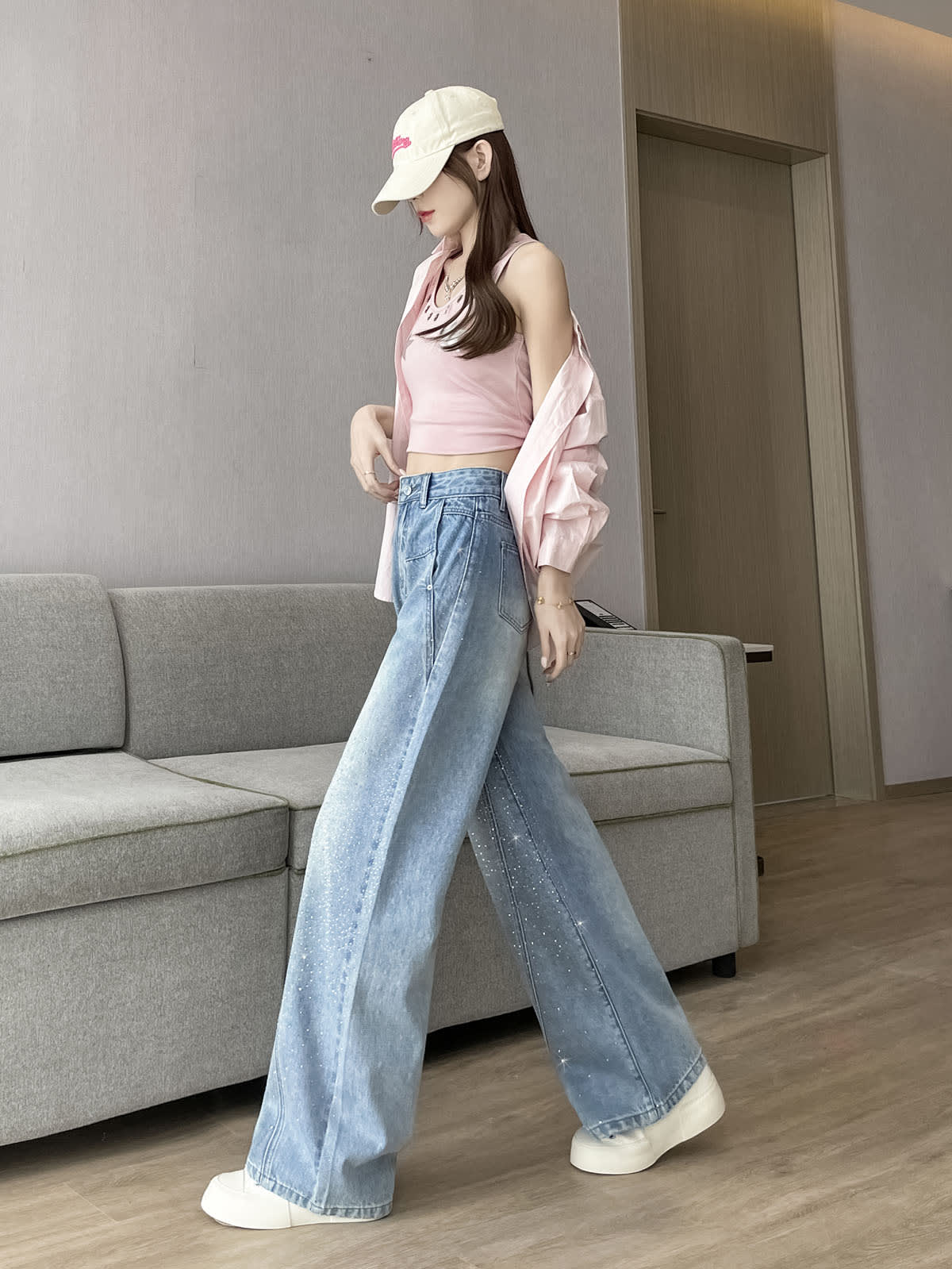 YEEYEEWang Wide-Leg Jeans in Light Blue, Asian-fit cut, full-body walking side view, shirt draped over shoulders, rhinestone denim flowing with movement.