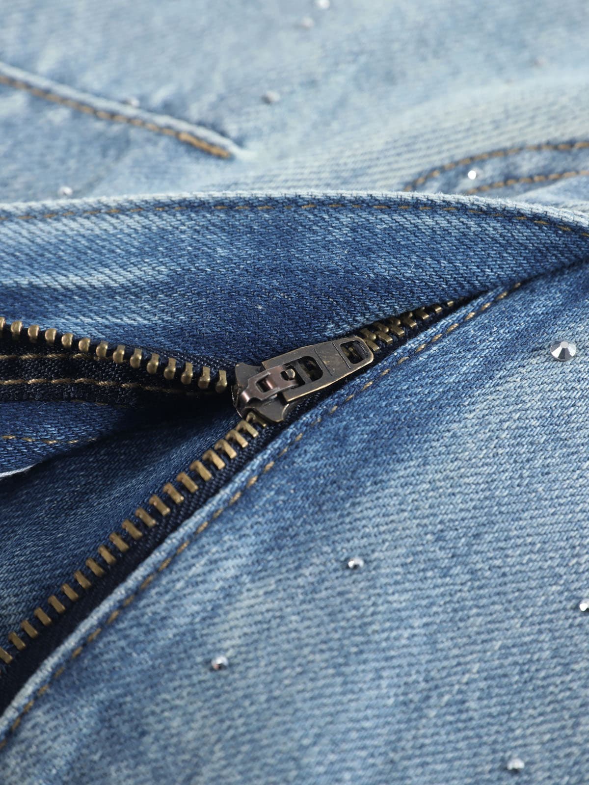 YEEYEEWang Wide-Leg Jeans in Light Blue, Asian-fit cut, close-up of fly with antique bronze zipper on faded denim, scattered rhinestones nearby.