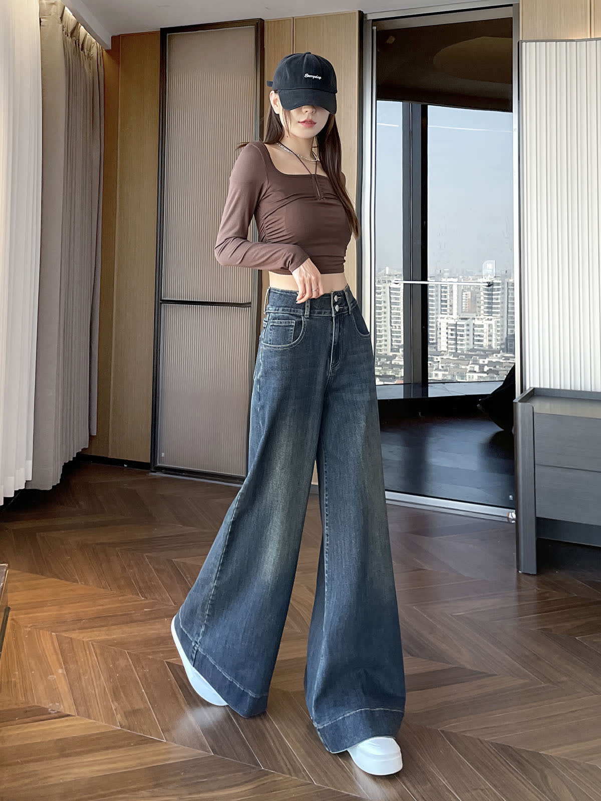 YEEYEEWang wide-leg jeans in Mid-Wash Blue, Asian-fit cut, full-body standing front pose in black cap, hand resting on waistband, city window backdrop.