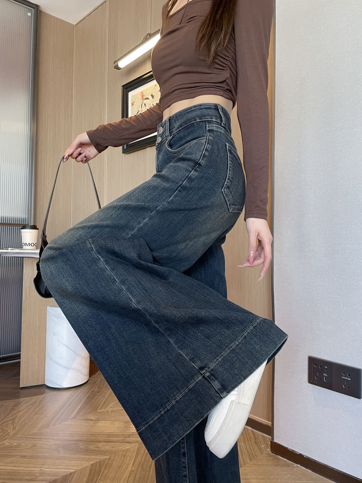 YEEYEEWang wide-leg jeans in Mid-Wash Blue, Asian-fit cut, waist-down side leg-kick pose holding black bag strap, cuffed hem lifted.