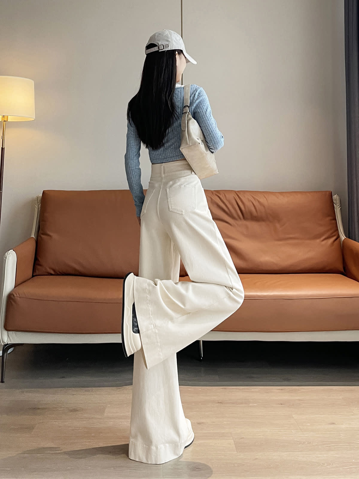 YEEYEEWang wide-leg jeans in Ivory, Asian-fit cut, full-body back leg-kick pose with beige shoulder bag, back patch pockets visible.