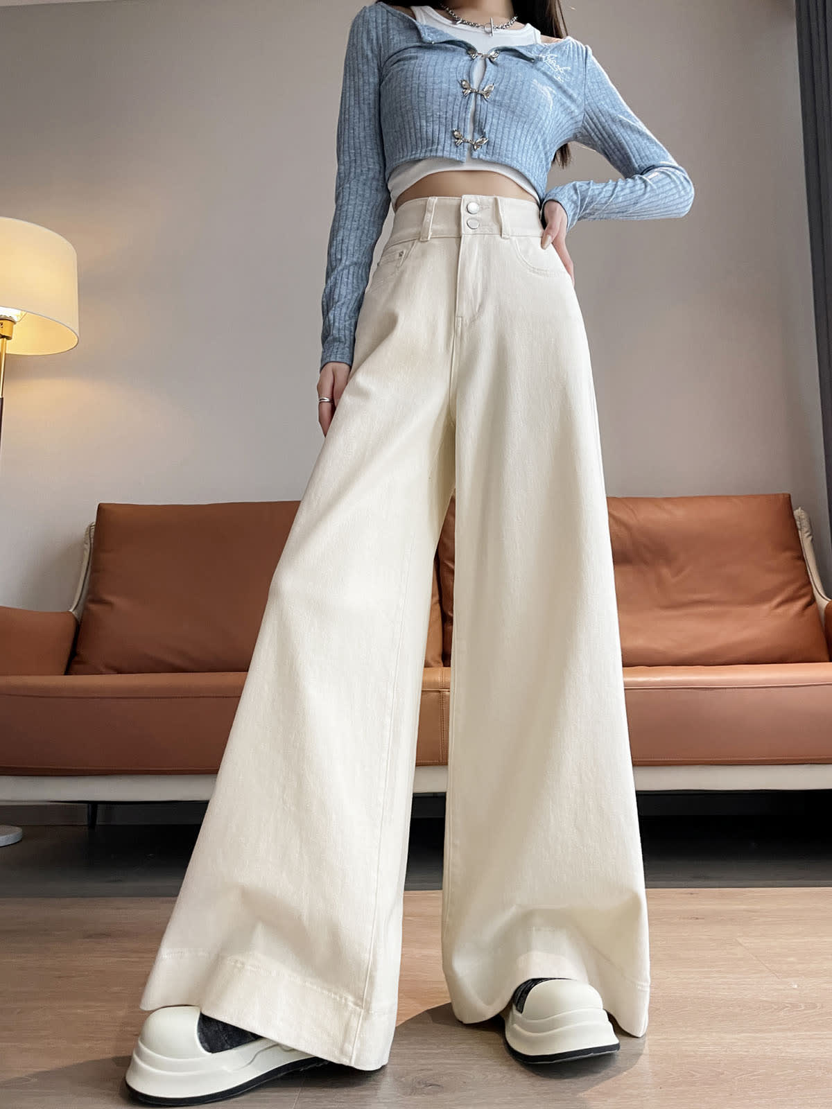 YEEYEEWang wide-leg jeans in Ivory, Asian-fit cut, waist-down front standing pose with one hand on hip, floor-sweeping drape over platform shoes.