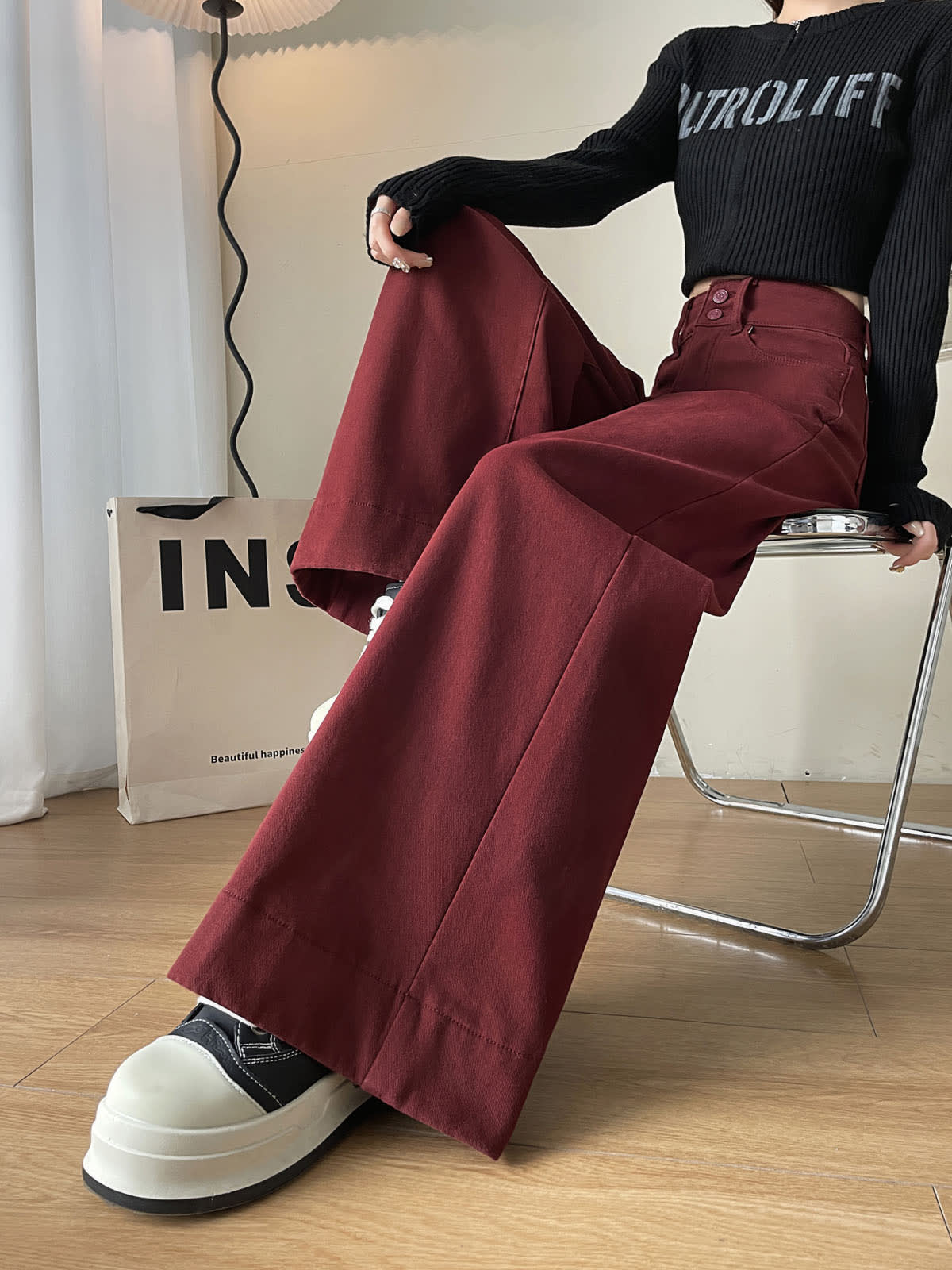 YEEYEEWang wide-leg jeans in Dark Cherry, Asian-fit cut, waist-down seated pose on chair with legs crossed, wide hem over chunky sneakers.