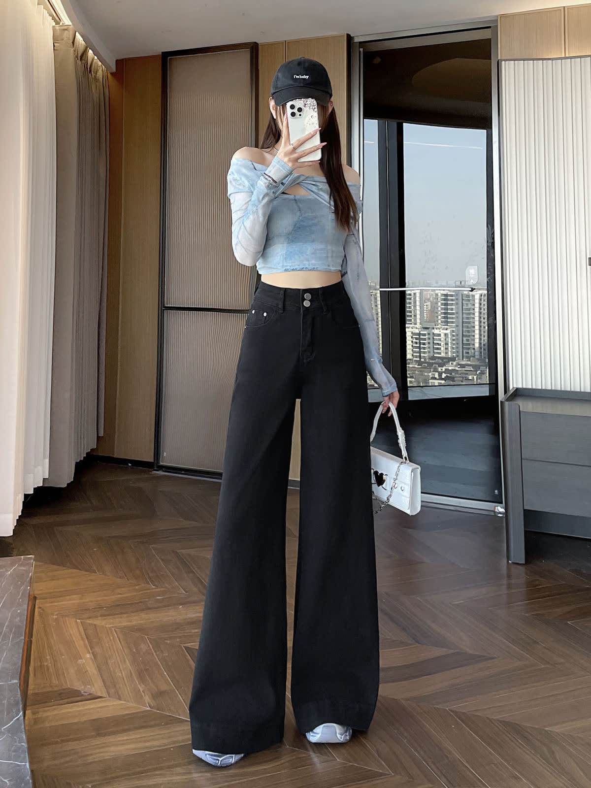 YEEYEEWang wide-leg jeans in Solid Black, Asian-fit cut, full-body front pose holding phone at face and white handbag, off-shoulder top and cap.