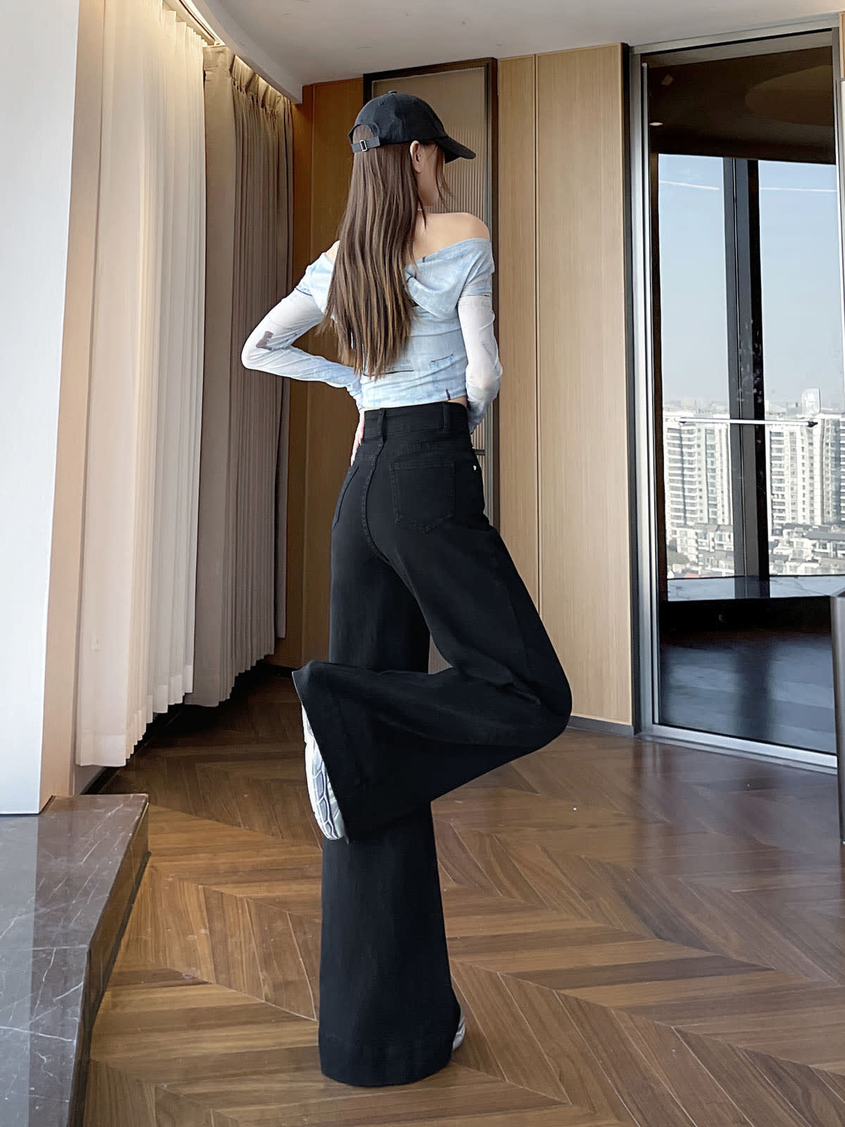YEEYEEWang wide-leg jeans in Solid Black, Asian-fit cut, full-body back leg-kick pose in black cap, off-shoulder top, back pockets visible.
