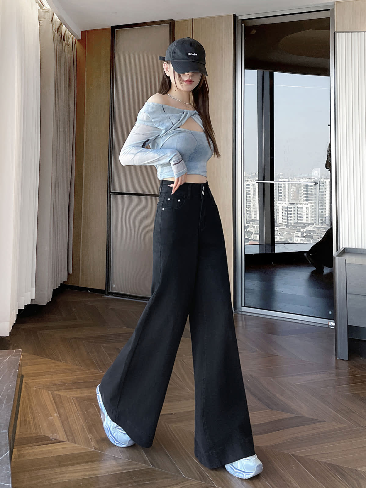 YEEYEEWang wide-leg jeans in Solid Black, Asian-fit cut, full-body standing front pose in black cap, hand near waistband, city window backdrop.