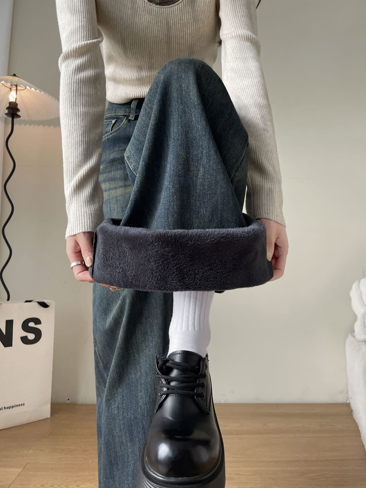 YEEYEEWang Fleece-Lined Wide-Leg Jeans in Mid-Wash Blue, close-up of both hands holding up folded cuff to show plush fleece lining, Asian-fit cut.