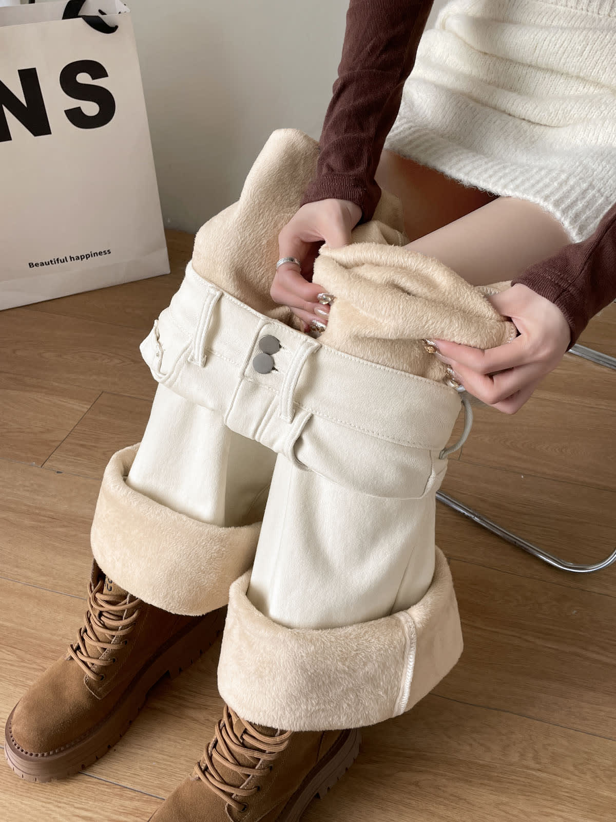 YEEYEEWang Fleece-Lined Wide-Leg Jeans in Ivory, close-up of seated model pulling open waist to reveal cream plush fleece lining, Asian-fit cut, variant thumbnail.