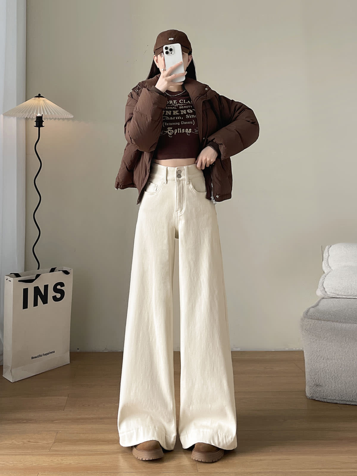 YEEYEEWang Fleece-Lined Wide-Leg Jeans in Ivory, full-body front standing view holding phone at face, brown puffer jacket and cap, Asian-fit cut.