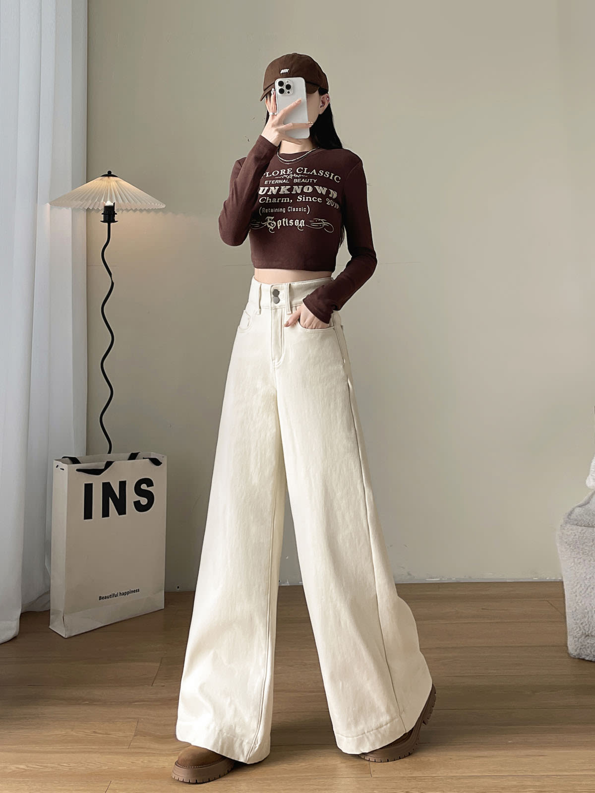 YEEYEEWang Fleece-Lined Wide-Leg Jeans in Ivory, full-body front standing pose holding phone at face, letter-print brown crop top and cap, Asian-fit cut.