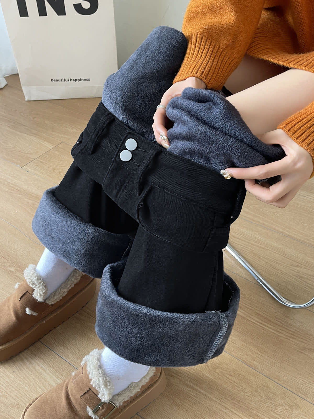 YEEYEEWang Fleece-Lined Wide-Leg Jeans in Solid Black, close-up of seated model pulling up pant leg to reveal grey plush fleece lining, Asian-fit cut, variant thumbnail.