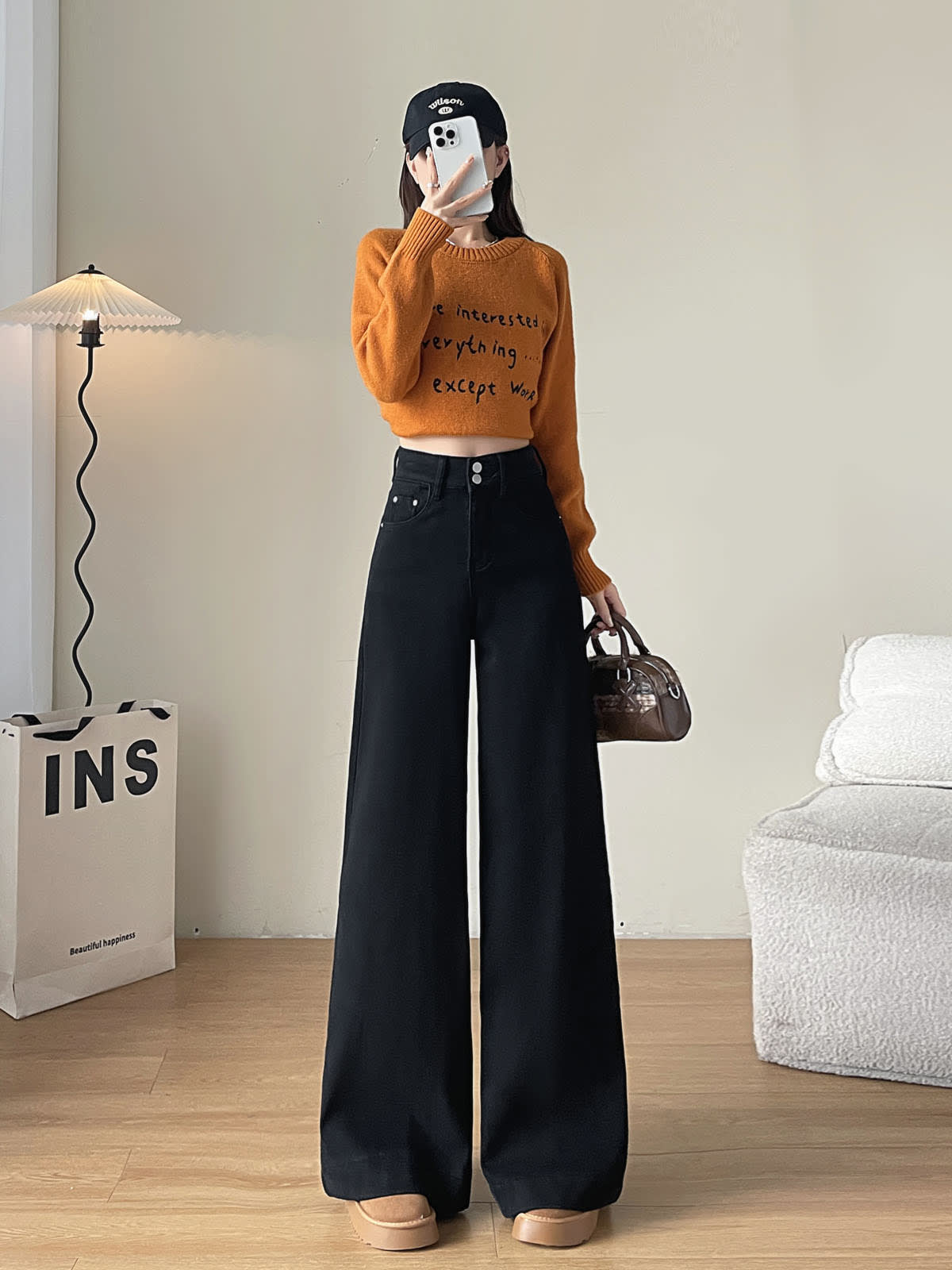 YEEYEEWang Fleece-Lined Wide-Leg Jeans in Solid Black, full-body front standing view holding phone at face and brown handbag, orange letter-print sweater, Asian-fit cut.