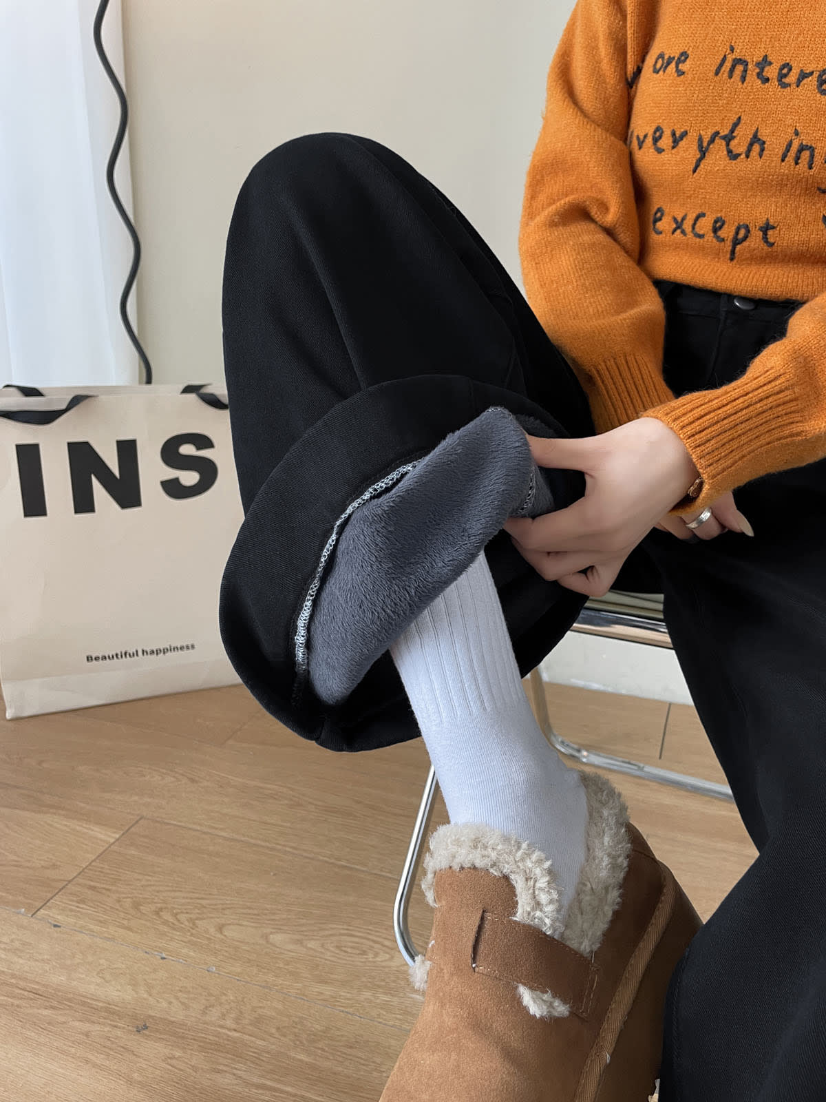 YEEYEEWang Fleece-Lined Wide-Leg Jeans in Solid Black, close-up of hand pulling open folded cuff to show grey plush fleece lining, Asian-fit cut.