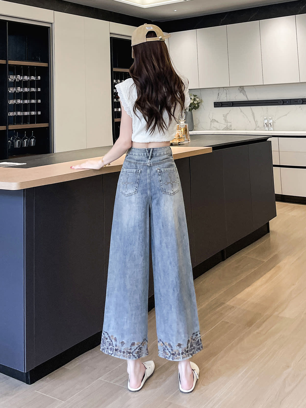 YEEYEEWang Wide-Leg Jeans in Light Blue, Asian-fit cut, full-body back view standing with hand on counter, back patch pockets and embroidered hems visible.