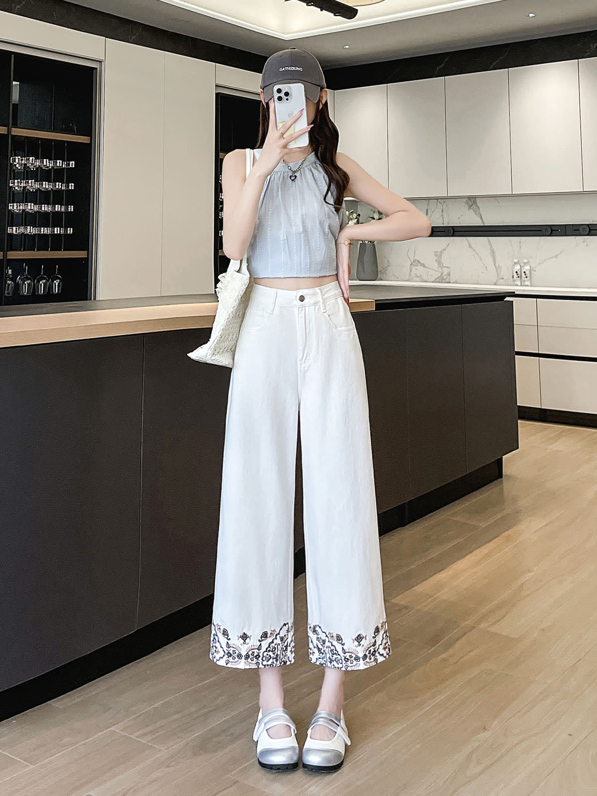 YEEYEEWang Wide-Leg Jeans in Ivory, Asian-fit cut, full-body front standing pose holding phone at face, grey cap and woven tote, floral embroidered hems.
