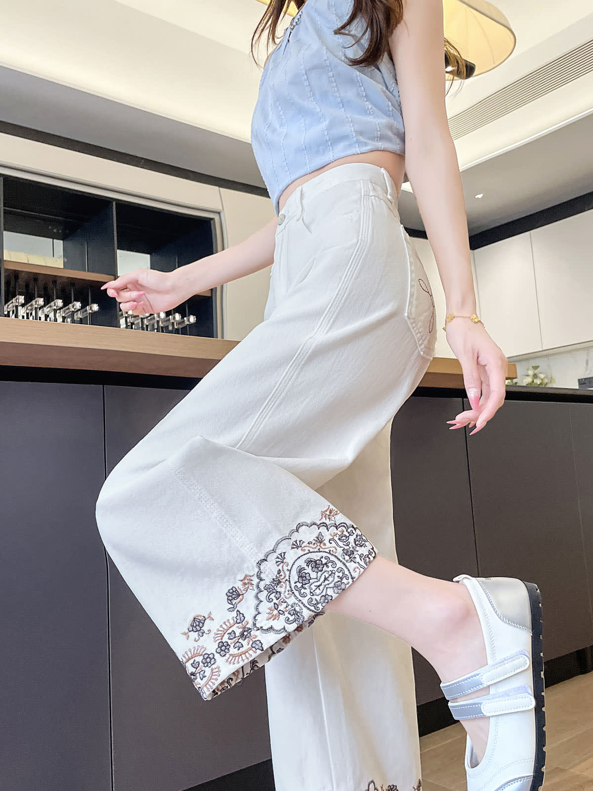 YEEYEEWang Wide-Leg Jeans in Ivory, Asian-fit cut, waist-down side view in leg-kick pose, fluid drape and floral embroidered hem in motion.