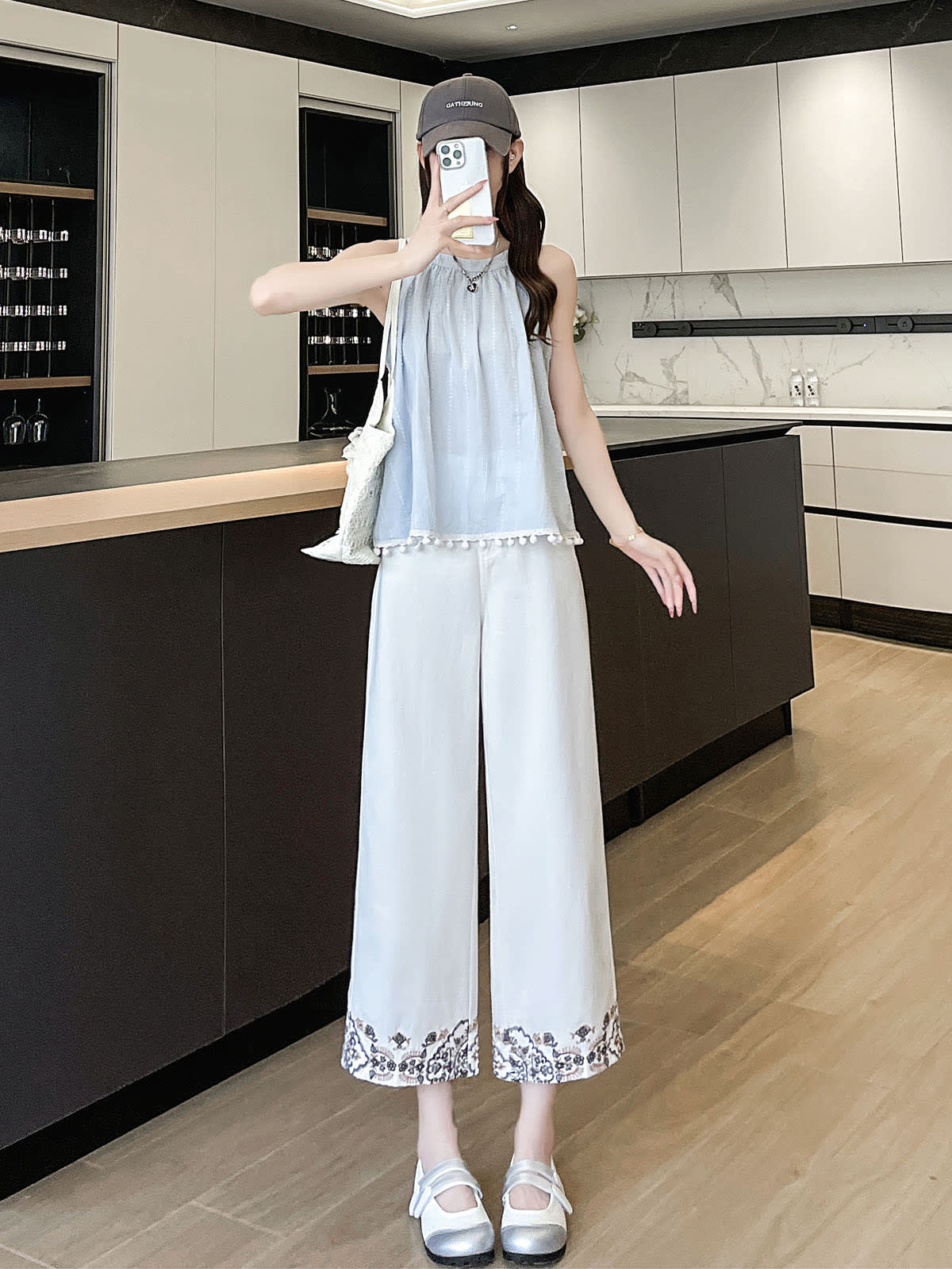 YEEYEEWang Wide-Leg Jeans in Ivory, Asian-fit cut, full-body front standing pose holding phone at face, blue halter top with pom-pom trim.