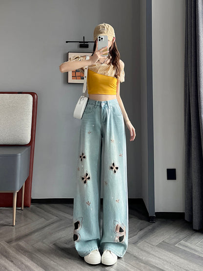 YEEYEEWang Wide-Leg Jeans in Light Blue, Asian-fit cut, full-body front pose holding phone at face, yellow off-shoulder top with beige cap and white shoulder bag, butterfly cutout embroidery, floor-sweeping drape.
