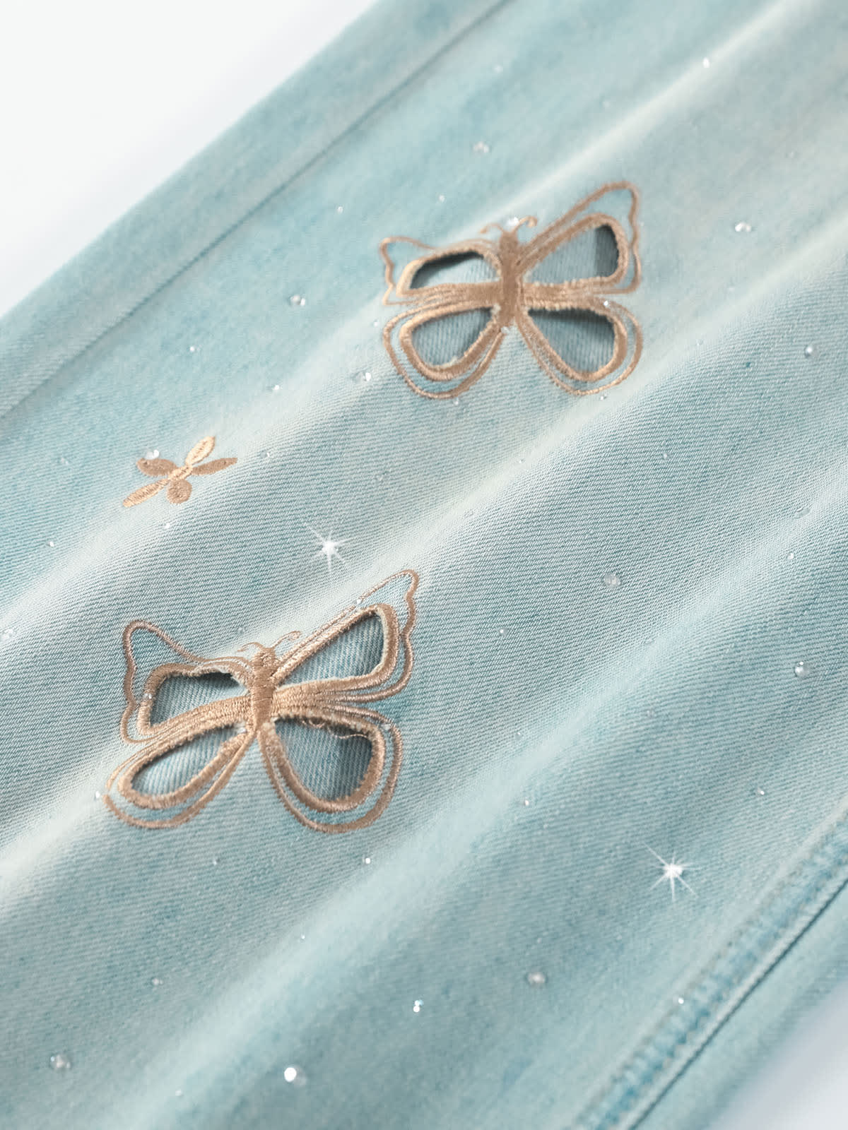 YEEYEEWang Wide-Leg Jeans in Light Blue, Asian-fit cut, close-up of butterfly embroidery and rhinestone accents on washed denim fabric.