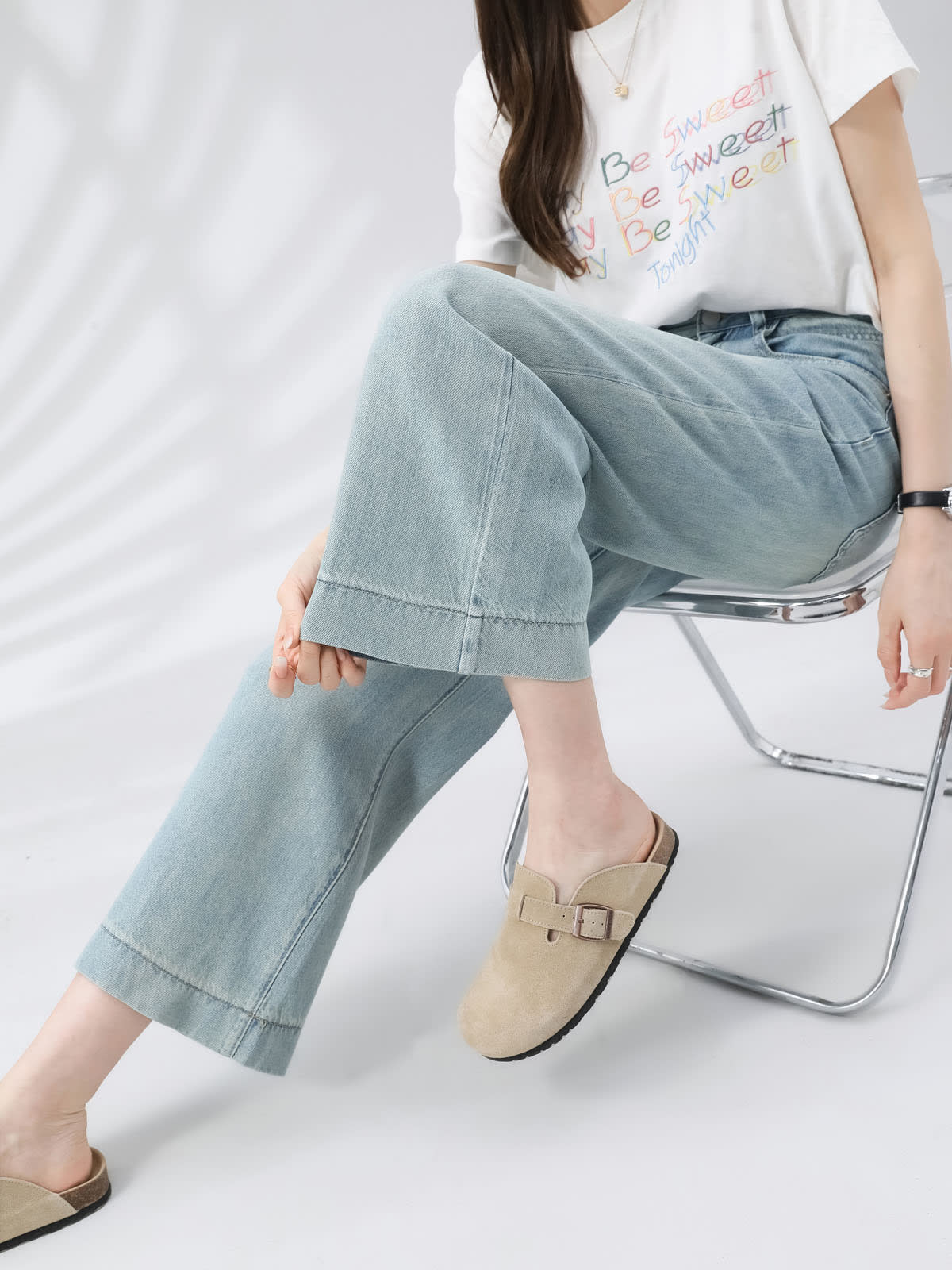 YEEYEEWang Wide-Leg Jeans in Light Blue, Asian-fit cut, waist-down seated pose on chair with one leg raised, tan clogs, relaxed wide-leg fall.