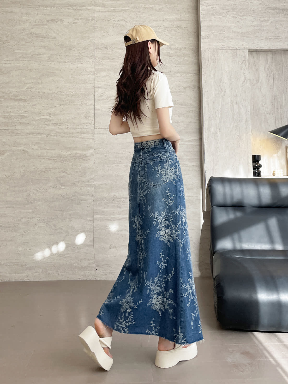 YEEYEEWang Jupe longue en jean Bleu, coupe Asian-fit, vue de dos corps entier, en marchant, casquette beige, denim à imprimé floral avec poches arrière plaquées et ourlet évasé en mouvement.