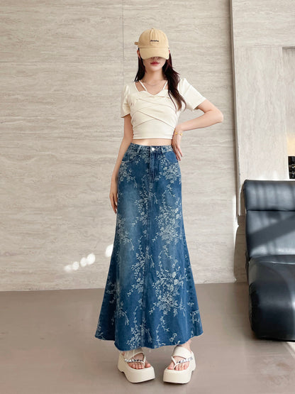 YEEYEEWang Jupe longue en jean Bleu, coupe Asian-fit, vue de face corps entier, debout main sur la hanche, casquette beige, denim à imprimé floral boutonné au drapé évasé balayant le sol.