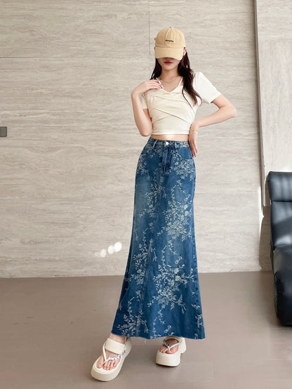 YEEYEEWang Jupe longue en jean Bleu, coupe Asian-fit, vue frontale pied-à-terre debout, une main au col et une sur la hanche, jean jacquard floral, casquette beige.