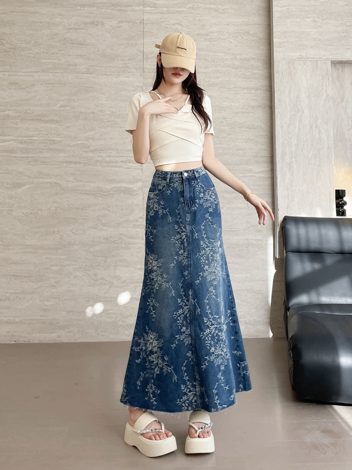 YEEYEEWang Jupe longue en jean Bleu, coupe Asian-fit, vue frontale pied-à-terre debout, une main levée vers la poitrine, jean jacquard floral, casquette beige.
