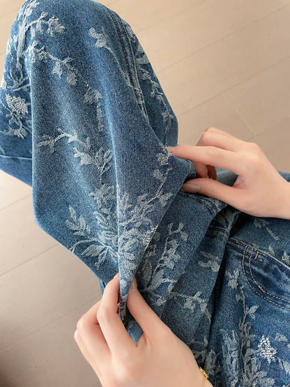 YEEYEEWang Jupe longue en jean Bleu, coupe Asian-fit, gros plan sur la texture du jean jacquard floral, mains soulevant le bord du tissu.