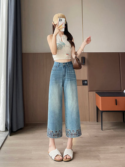 YEEYEEWang Straight Jeans in Vintage Blue, Asian-fit cut, full-body front standing pose holding phone at face, cap and brown shoulder bag, floral-embroidered hems.
