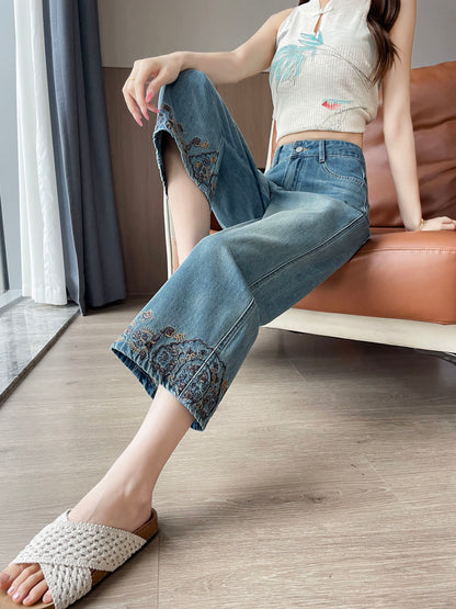 YEEYEEWang Straight Jeans in Vintage Blue, Asian-fit cut, waist-down seated pose leaning back on sofa with legs crossed, floral-embroidered hems in close view.
