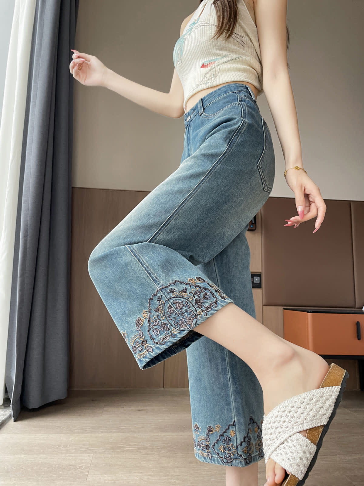YEEYEEWang Straight Jeans in Vintage Blue, Asian-fit cut, waist-down side view leg-kick pose, embroidered paisley hem detail highlighted.