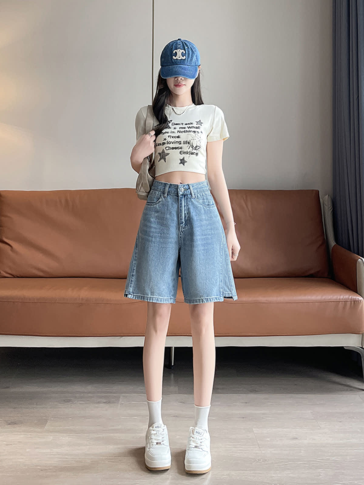 YEEYEEWang Denim Bermuda Shorts in Blue, Asian-fit cut, full-body front standing pose with a shoulder bag slung over one shoulder, styled with denim cap and white sneakers.
