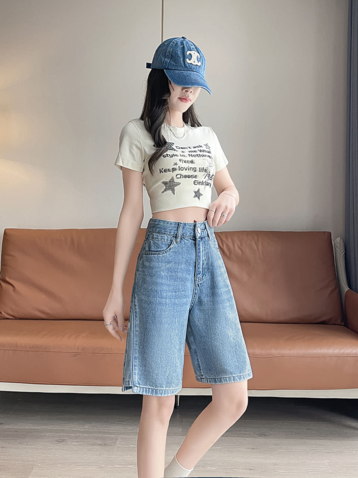 YEEYEEWang Denim Bermuda Shorts in Blue, Asian-fit cut, full-body front three-quarter standing pose with hand resting near the waistband, paired with a denim cap.