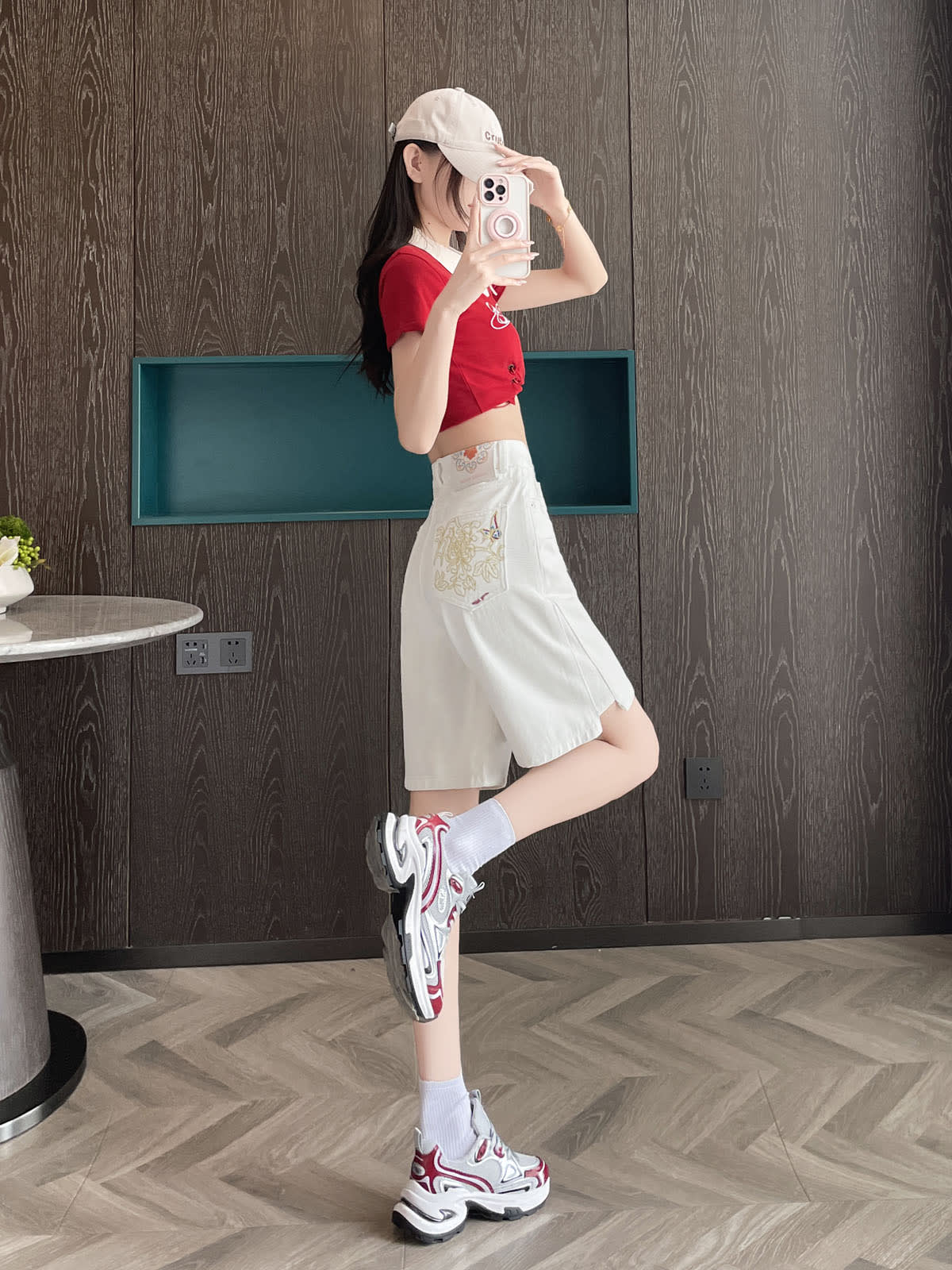 YEEYEEWang Denim Bermuda Shorts in White, Asian-fit cut, full-body side view with leg kicked back, phone held at face, embroidery visible on back pocket.