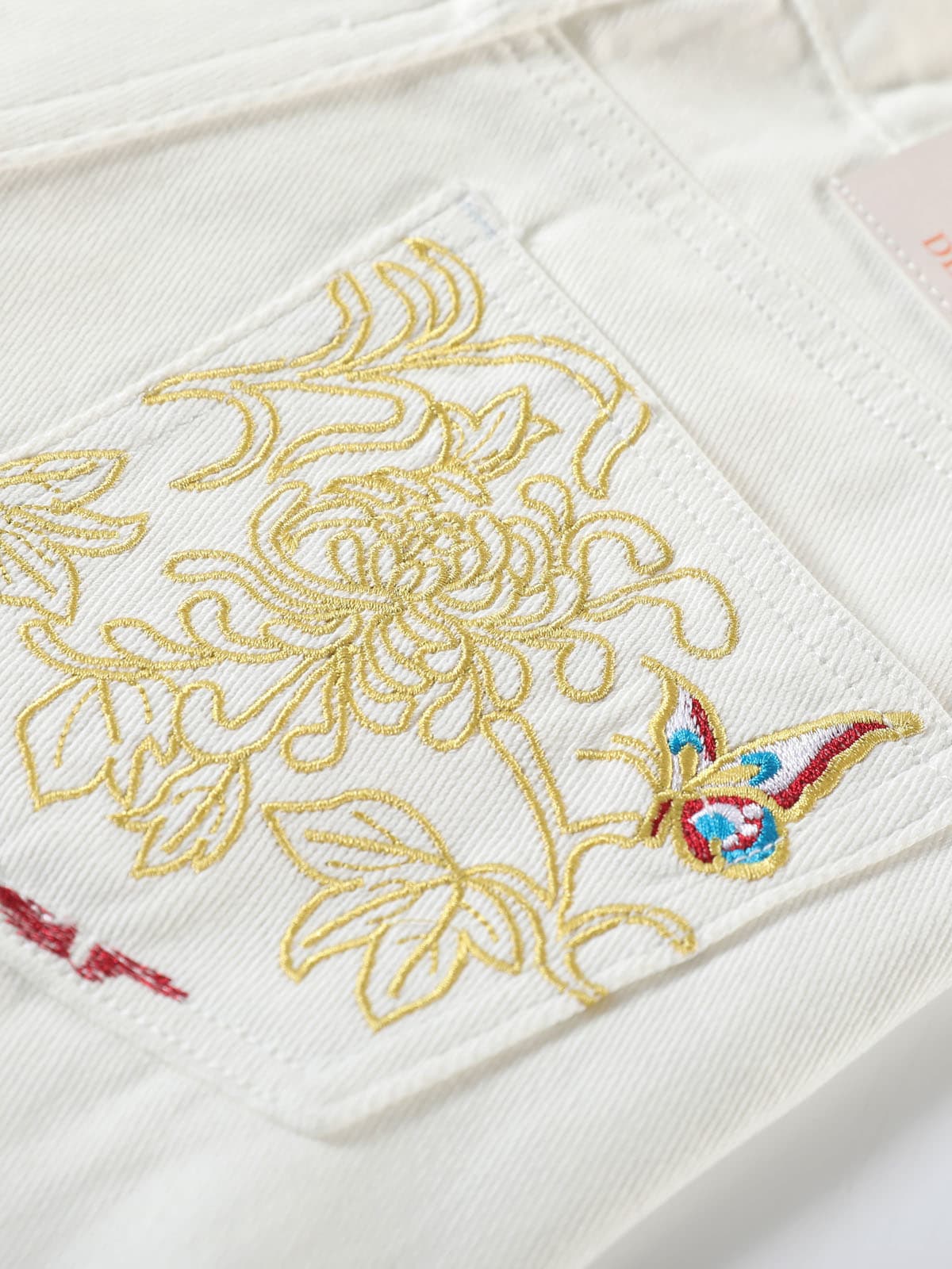 YEEYEEWang Denim Bermuda Shorts in White, Asian-fit cut, close-up of back patch pocket with floral and butterfly embroidery.