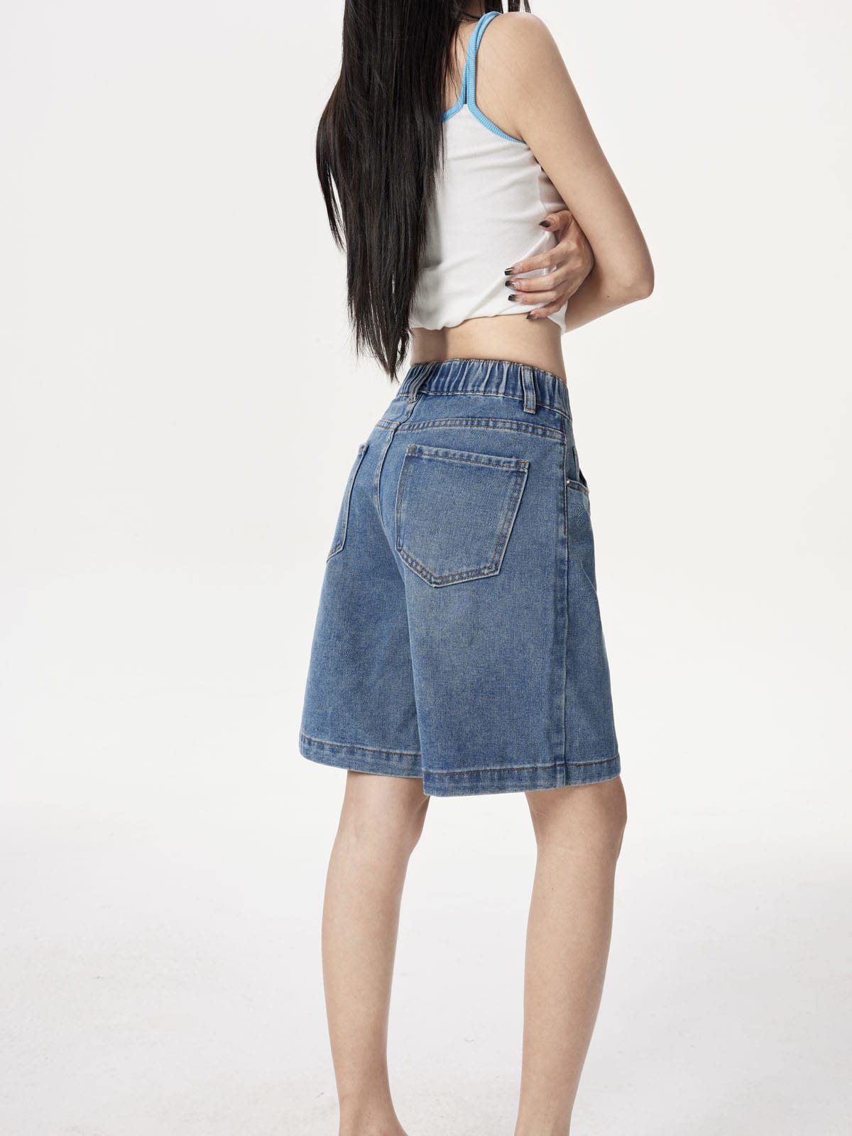 YEEYEEWang Denim Bermuda Shorts in Blue, Asian-fit cut, waist-down back-side view highlighting the back patch pocket and elastic-back waistband in motion.